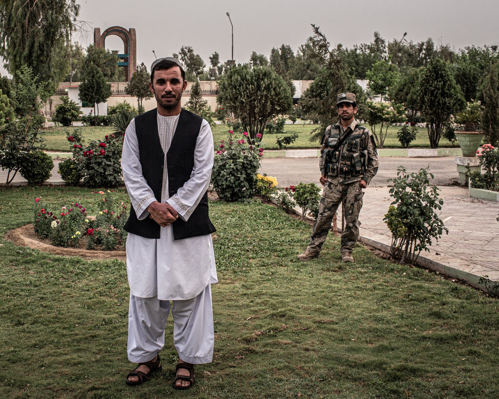 A man in traditional Afghan attire with his hands clasped at his waist