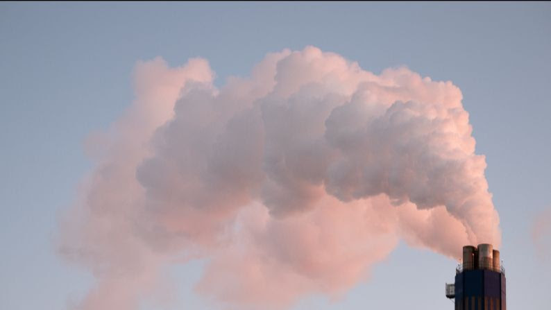 a factory chimney spewing smoke into a blue sky