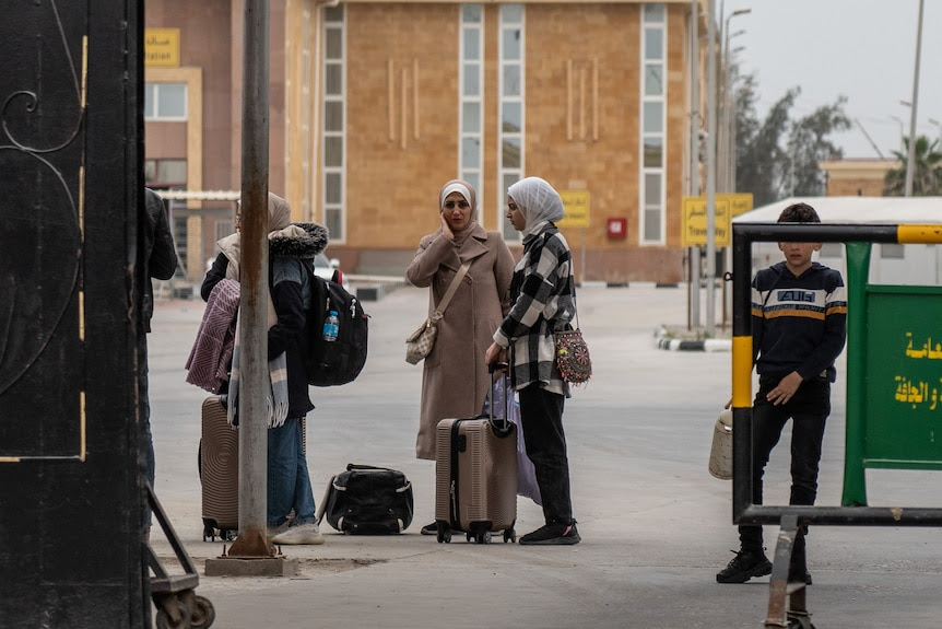 A family is checked by an official near a truck.