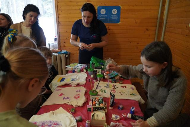 Teacher from Ukraine teaching from a paper on a partical boards