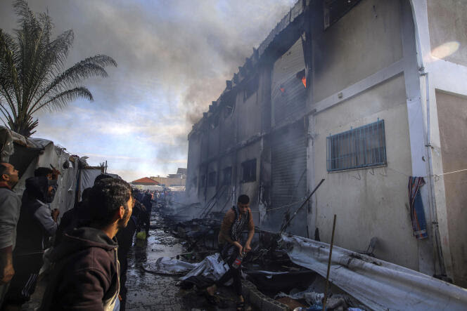 Des Palestiniens tentent d’éteindre un incendie dans un bâtiment de l’UNRWA que des personnes déplacées utilisent comme abri, après avoir été pris pour cible par des chars israéliens à Khan Younès, dans le sud de la bande de Gaza, le 24 janvier 2024. 