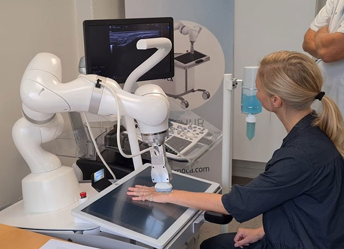 photo of A Woman has her wrist scanned by an ultrasound scanner called ARTHUR