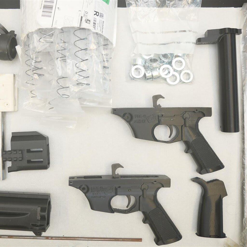 Disassembled firearm parts are laid out on display. 