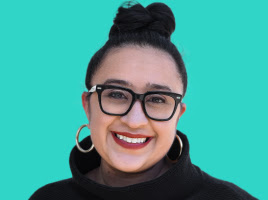 Smiling WOC with a red shirt, black jacket and red lipstick