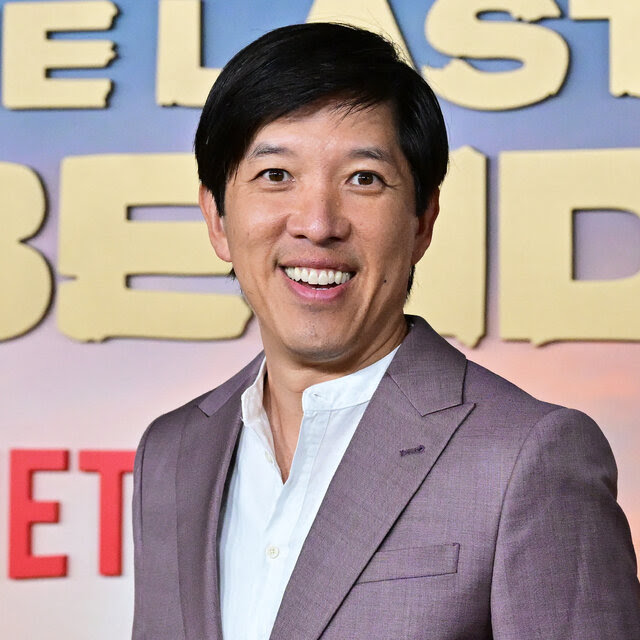 Dan Lin, wearing a suit coat and white shirt, standing in front of a sign for “The Last Airbender.”