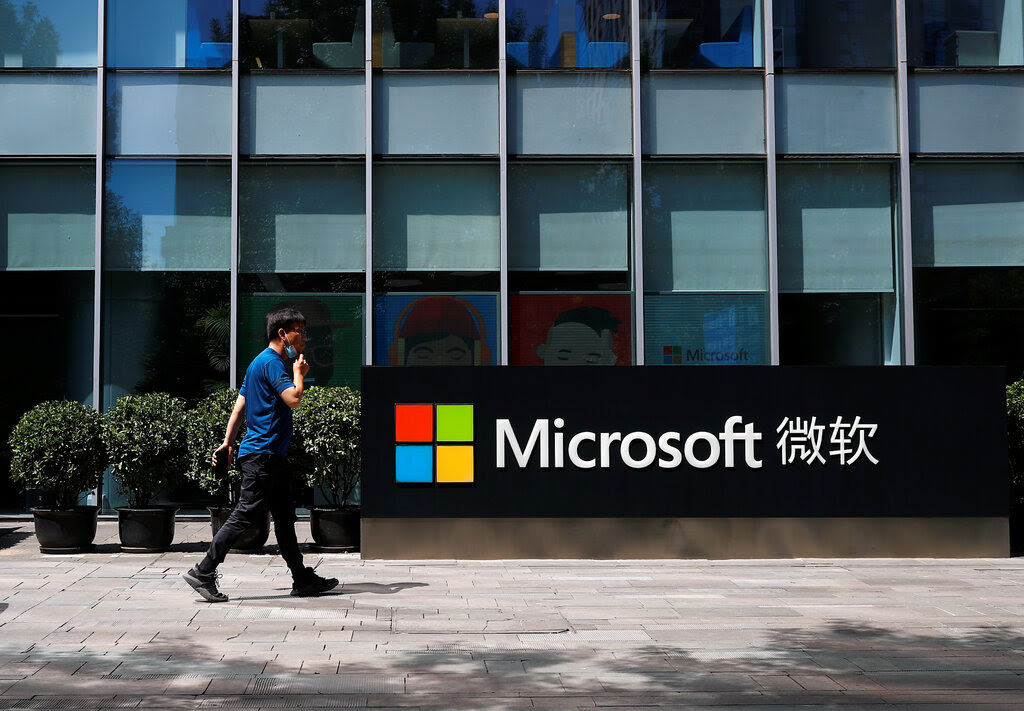 A sign on a plaza outside an office building displays Microsoft’s name and logo next to Chinese characters.