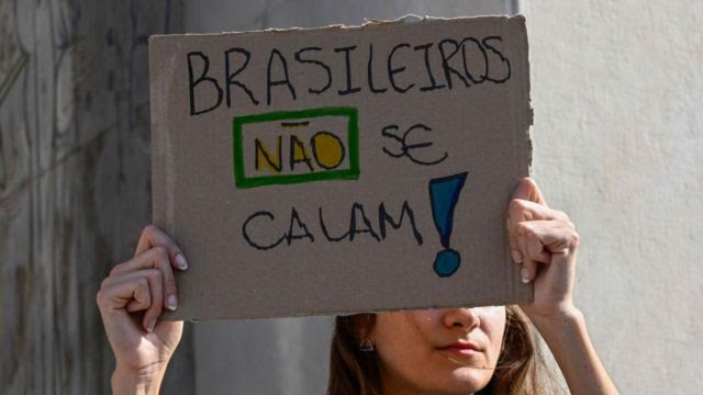 Mulher brasileira com placa 'brasileiros não se calam!'