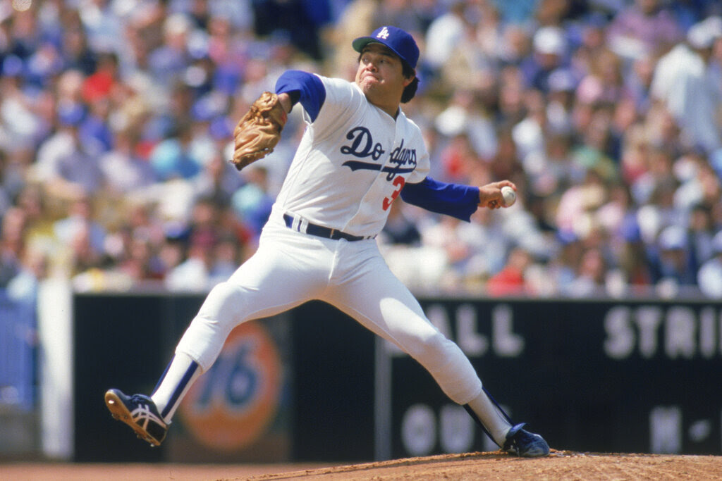 A man in a baseball uniform throws a pitch.