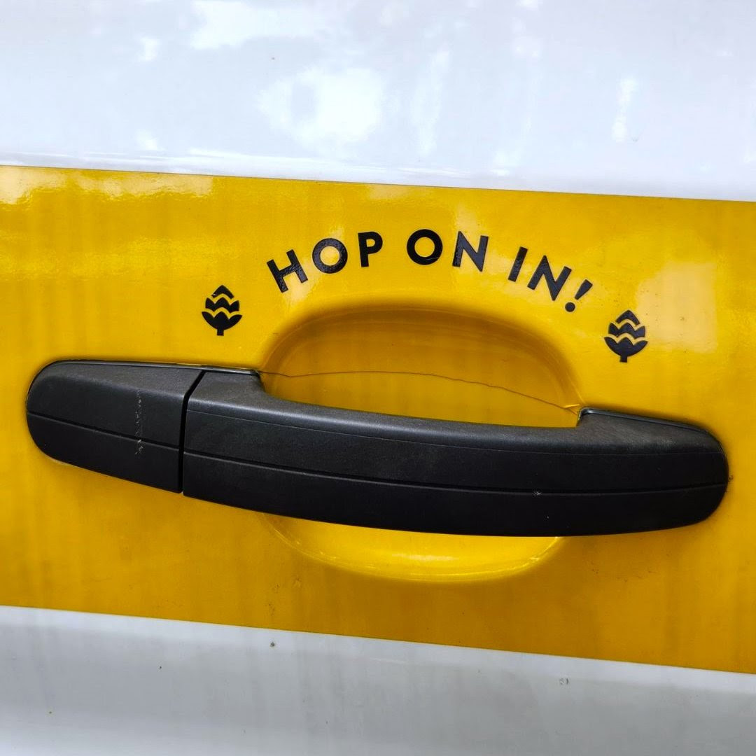 Close up shot of the GLBC brewpub shuttle handle, with the phrase "Hop on in!" and a yellow background.