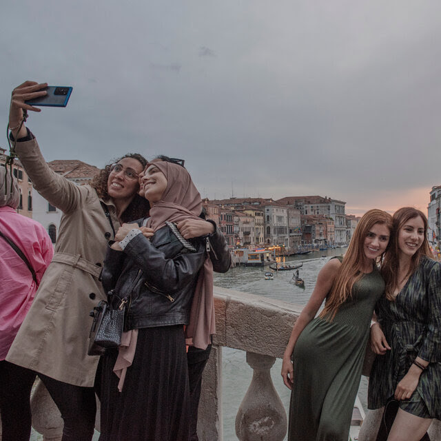 People take photos and selfies from a bridge overlooking the Grand Canal in Venice.