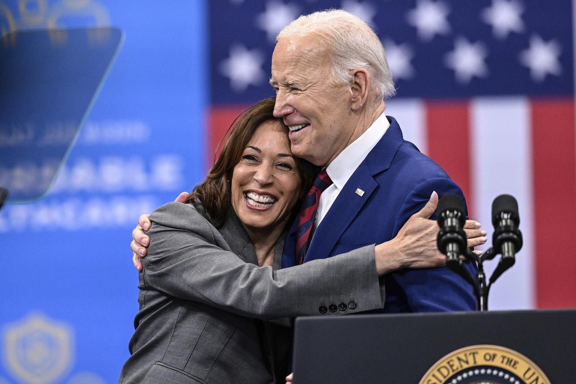 Vice President Kamala Harris,  left, embraces President Joe Biden after a speech in March 2024. They are behind a podium and an American flag is in the background.