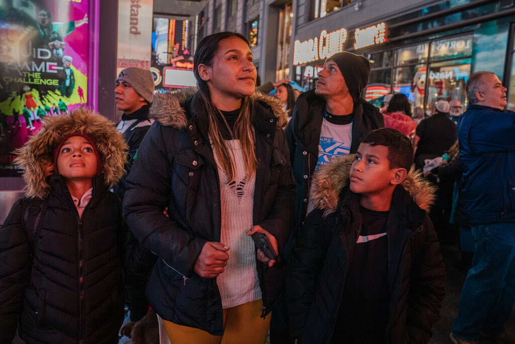 The family, wearing winter coats with furry hoods, stands in Times Square.