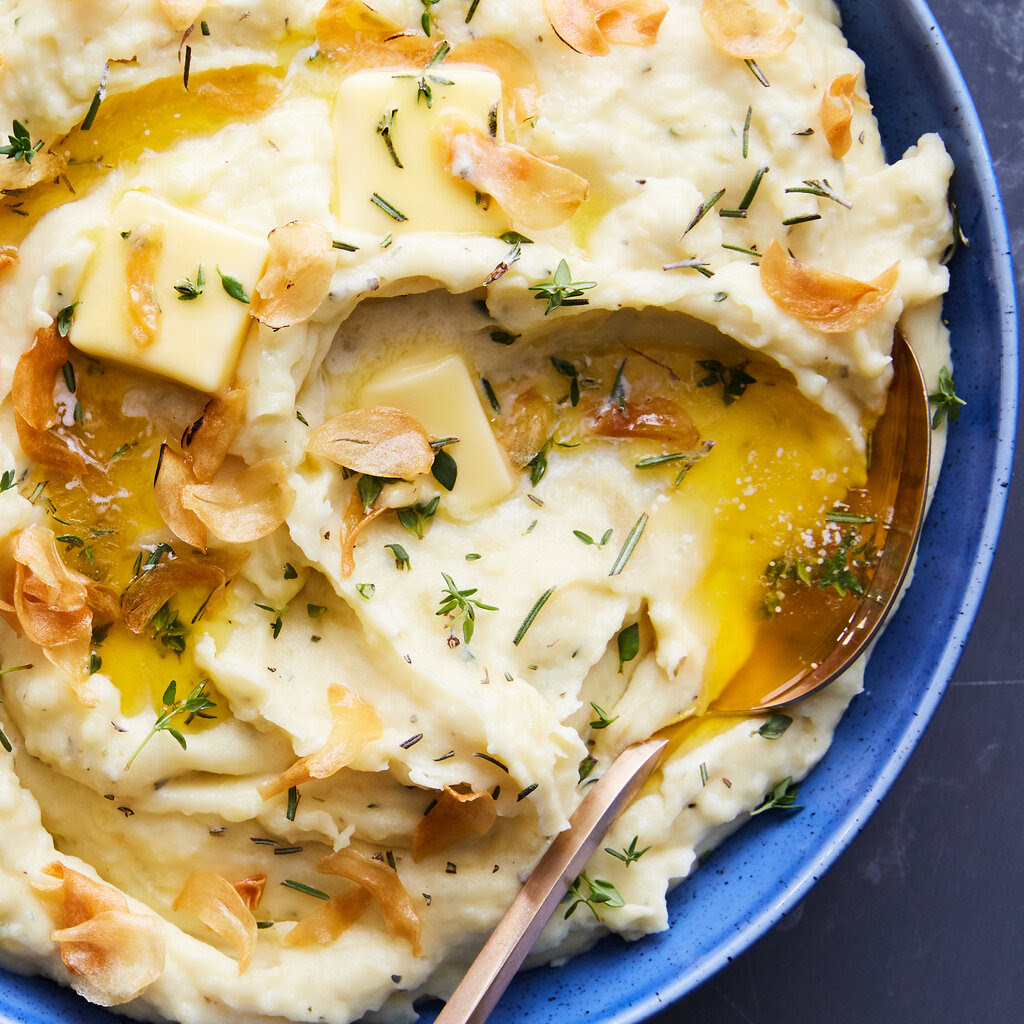 Mashed potatoes topped with melting butter, chopped herbs and thin slices of crispy garlic.