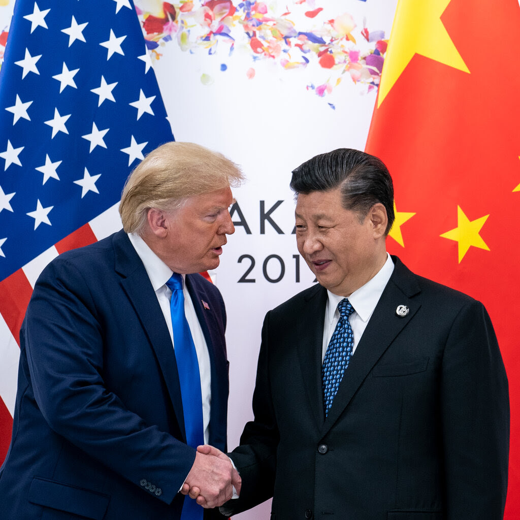 Donald Trump, left, shaking hands with Xi Jinping in 2019. The flags of the United States and China are behind them.