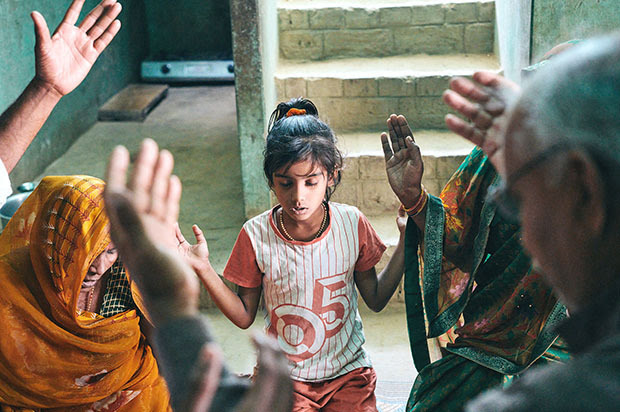 Several people, including a young girl, praying