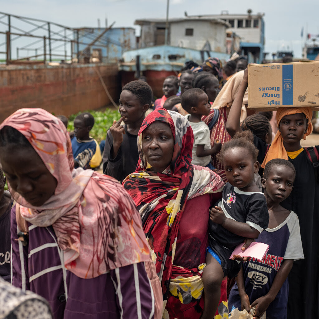 A line of people waiting to board a barge.