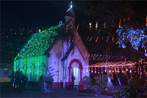 A small church shines in the night with colourful Christmas lights.