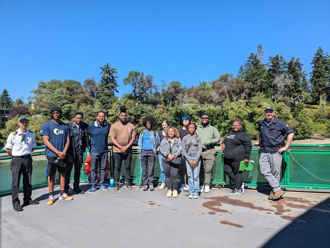 Several people posing for a photo on the outdoor deck of a ferry