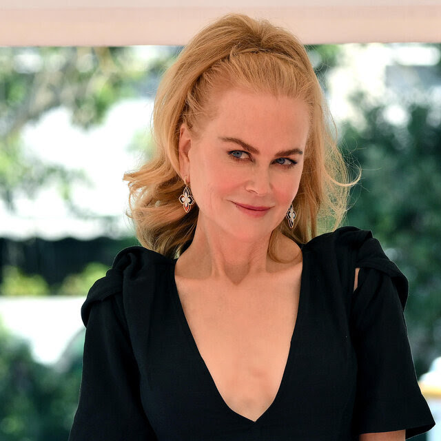 With the boat she's on blurred out, Nicole Kidman, in a black V-neck dress and her hair pulled back, smiles in a knowing way.