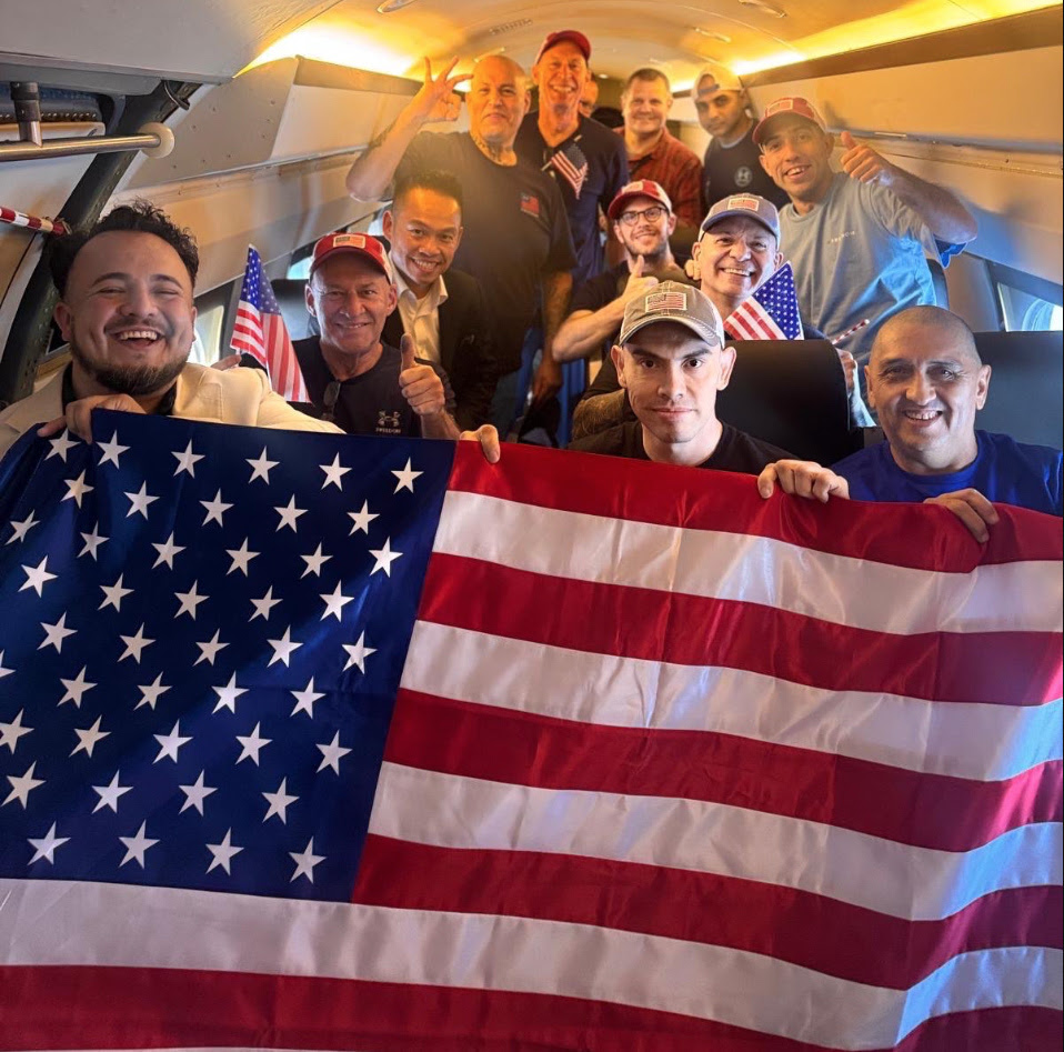 Passengers seated on an aircraft holding up an American flag.
