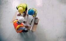Construction workers in protective gear, discussing a project around a table