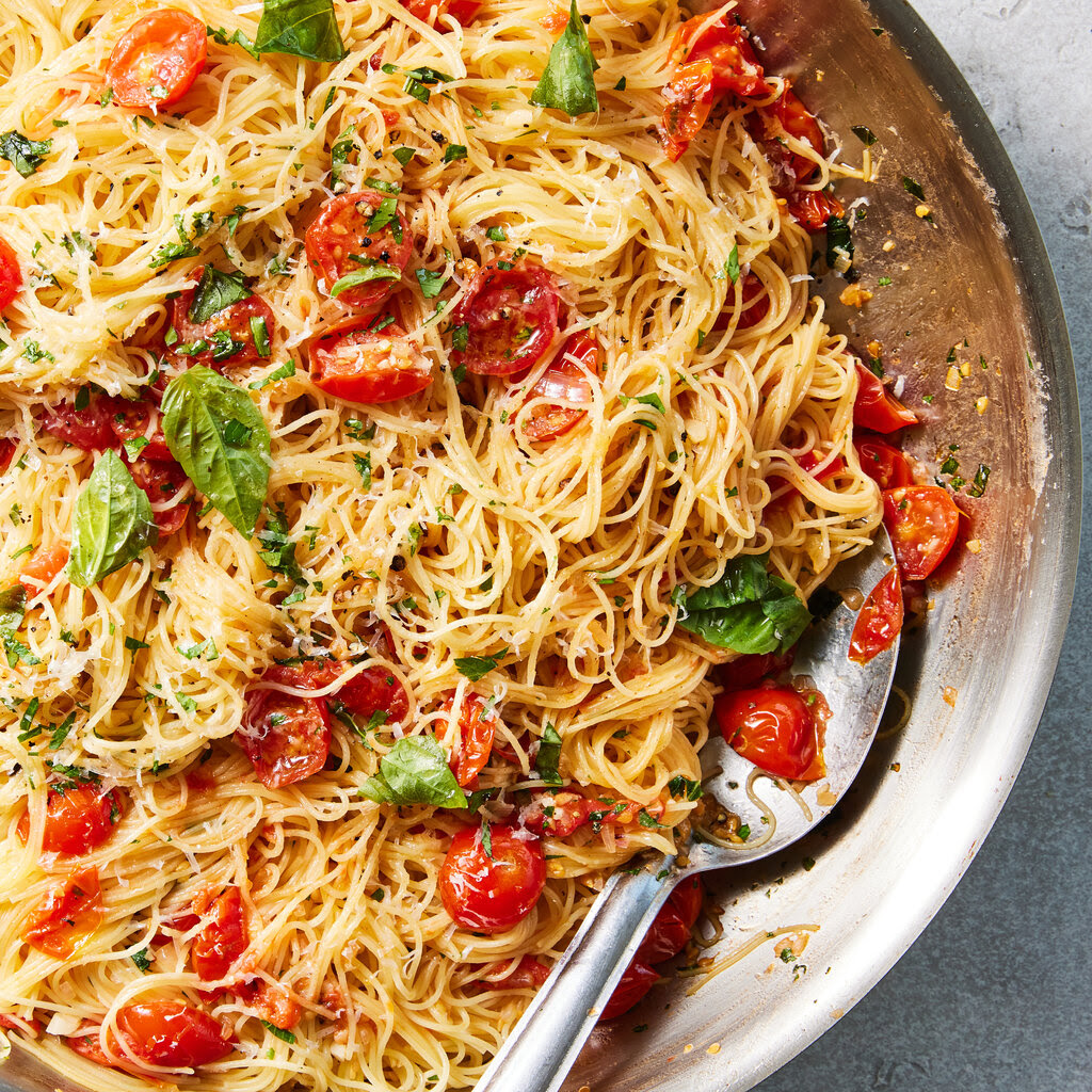 A bowl of angel hair pasta with cherry tomatoes.