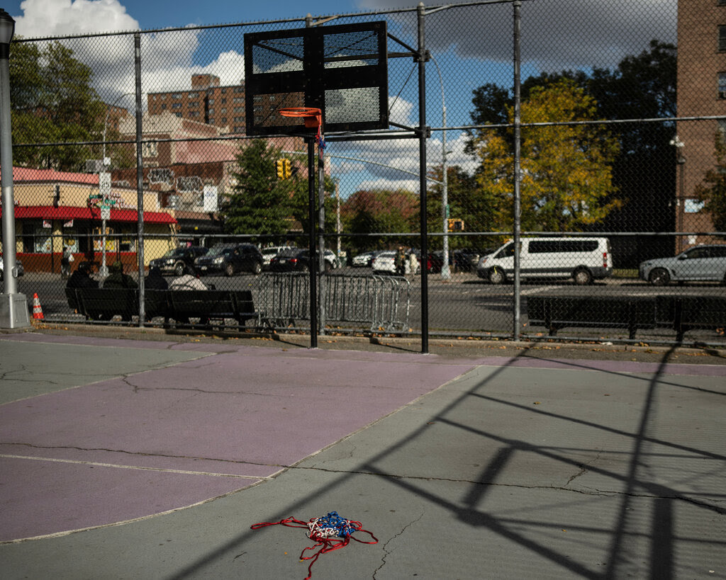 An empty basketball court. A torn net is crumpled on the floor. 