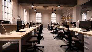 a spacious, industrial-style office setting with high arched windows, white walls, and rows of minimalist desks paired with ergonomic office chairs, creating a modern and functional workspace.