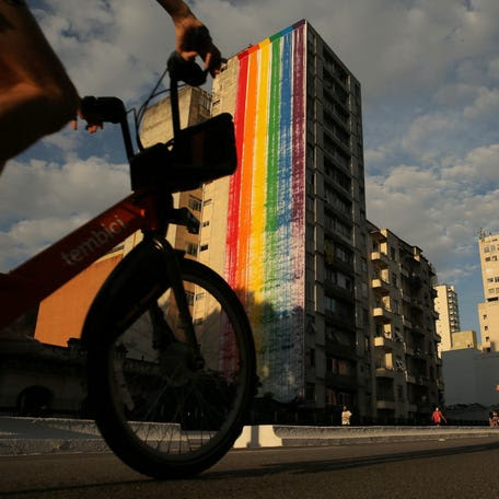 A man rides his bicycle in front of a building with wall painted by Facebook with the LGBT flag colours as a part of the pride month celebrations, in Sao Paulo, Brazil, June 6, 2021.