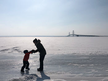 Child and adult holding hands on ice