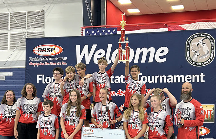 2nd place team gathers on winners’ podium holding check for $5,000, prize bow and 2nd place team trophy.