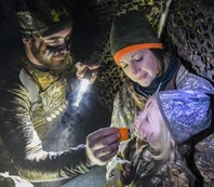 waterfowl hunter putting camo paint on child's face