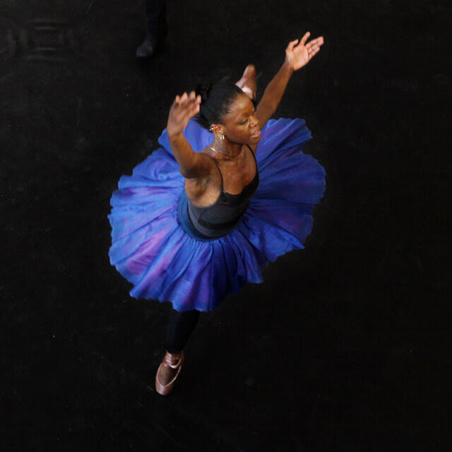 Ms. DePrince, in a blue ballet skirt, appears to be twirling. 