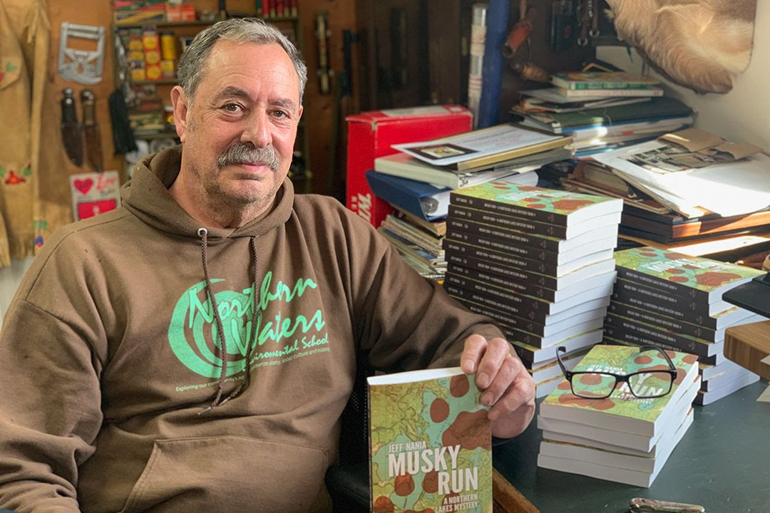 Jeff Nania sitting at a desk in front of piles of Musky Run books waiting to be signed.