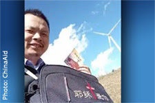 Chen Wensheng is smiling and holding a backpack and a piece of literature.