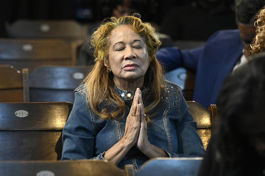 A woman with her eyes closed holds her hands together in prayer.