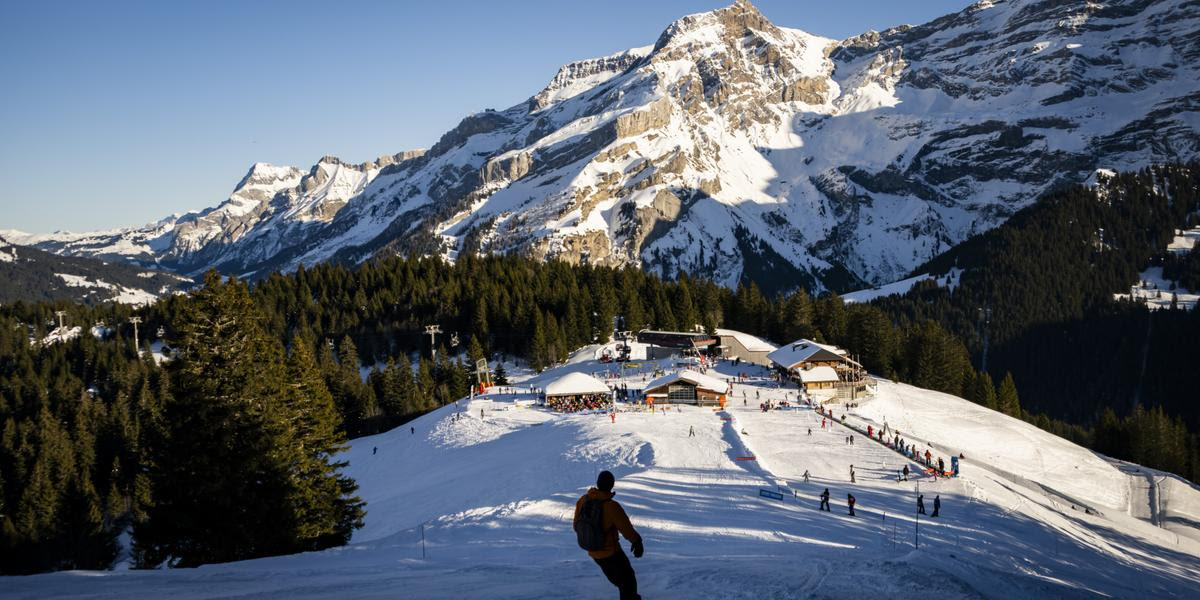 Des skieurs profitent de la neige et du soleil pour faire du ski sur une piste des Diablerets, en utilisant l'abonnement Magic Pass le lundi 30 decembre 2024 sur le domaine skiable de Villars-Gryon-Les Diablerets dans les Alpes vaudoises. (KEYSTONE/Jean-Christophe Bott)