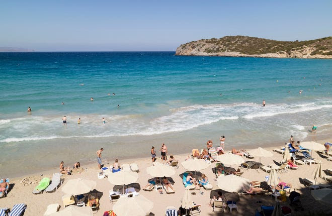 Playa Voulisma al sur de Agios Nikolaos, Creta, Grecia. Turistas en las arenas doradas.