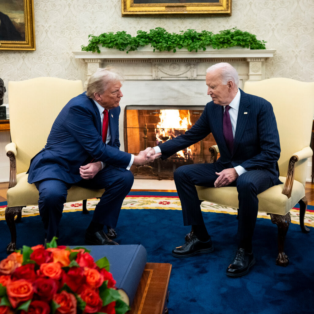 Donald Trump and President Biden shake hands while seated wearing suits. 