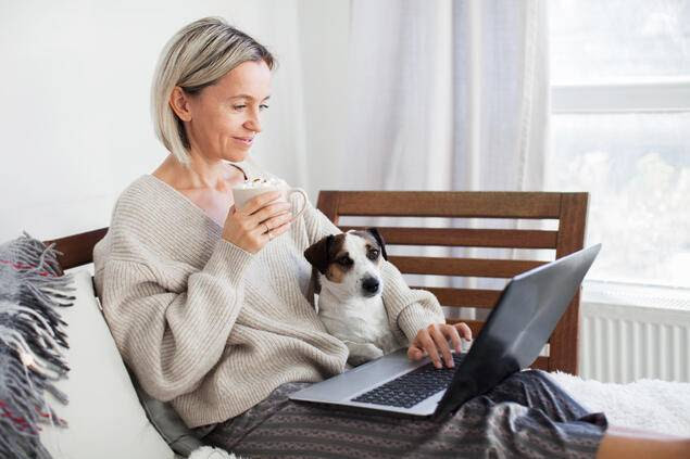 Dame jobber på PC sammen med sin hund