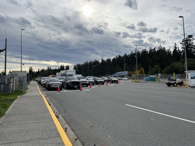 Anacortes terminal vehicle holding lanes with cars lined up between orange traffic cones, under a cloudy sky