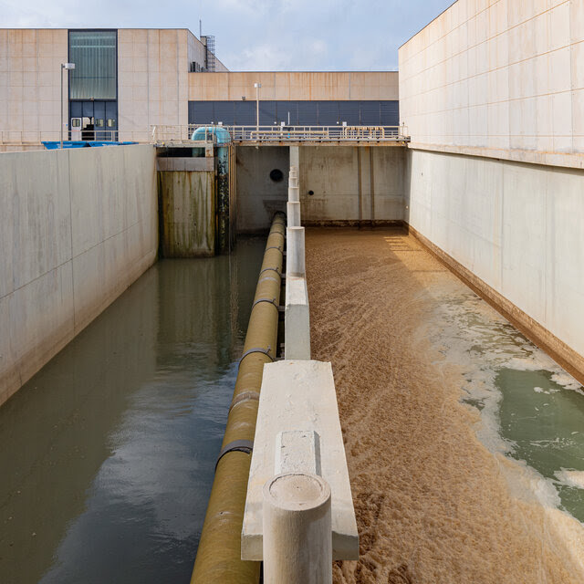 Two levels of water passing through a desalination plant with pipes and walls on either side. 