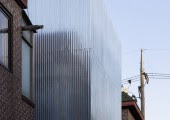 La fachada de acero contrasta con las fachadas de las viviendas de alrededor, realizadas con ladrillo rojo.