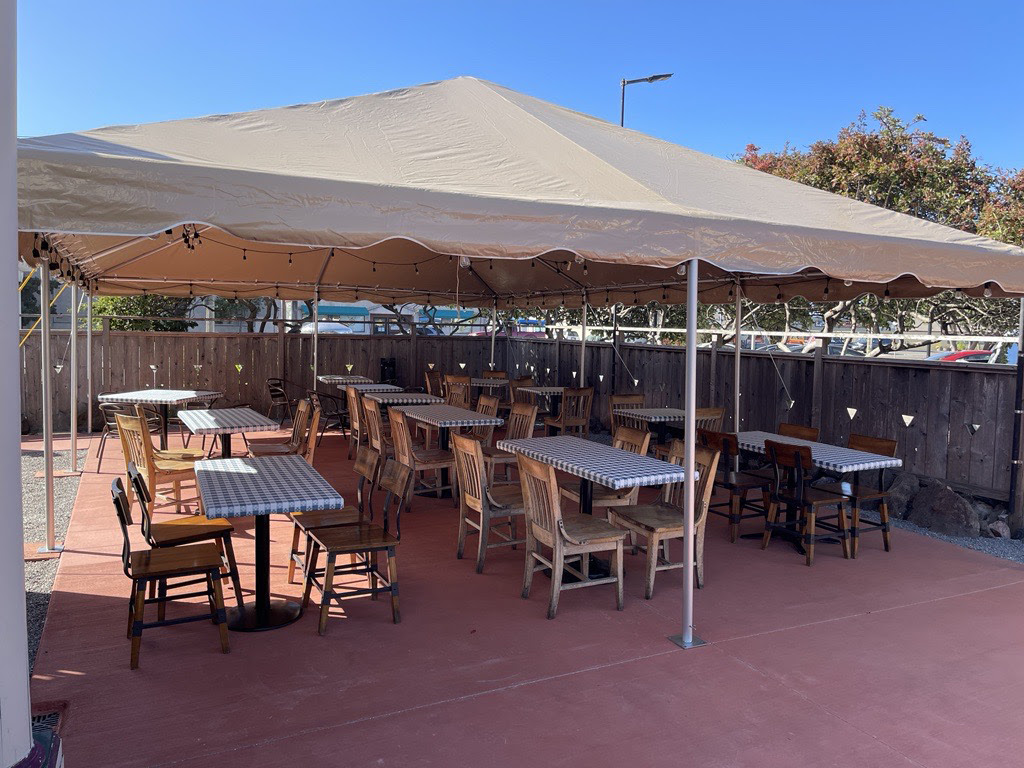 Tables under a tan tent on an outdoor patio