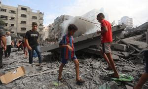 Los niños caminan entre los escombros de las casas destruidas por los ataques aéreos en el campo de refugiados de Al Shati en Gaza.