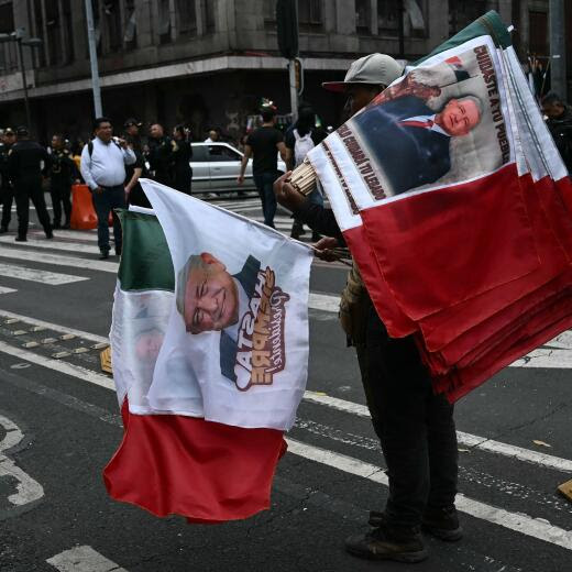 A man sells Mexican flags depecting Mexican President Andres Manuel Lopez Obrador before the 'Grito de Independencia' ceremony, which marks the start of Independence Day celebrations near El Zocalo Square in Mexico City on September 15, 2024. (Photo by CARL DE SOUZA / AFP)