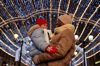 Black father and daughter embracing outdoors with lights