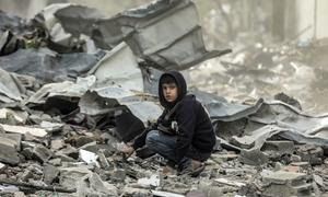 Un niño sentado en los escombros observa la destrucción del barrio Al-Touam en el norte de la Franja de Gaza.