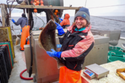 Leah Jones holds up a flat fish aboard a boat on open water