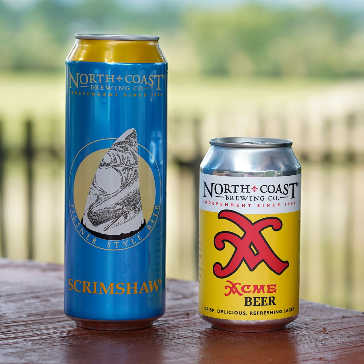 19.2oz can of Scrimshaw and 12oz can of Acme Beer on a table outdoors.